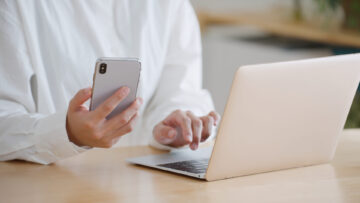 スマホを見てパソコンに入力する女性